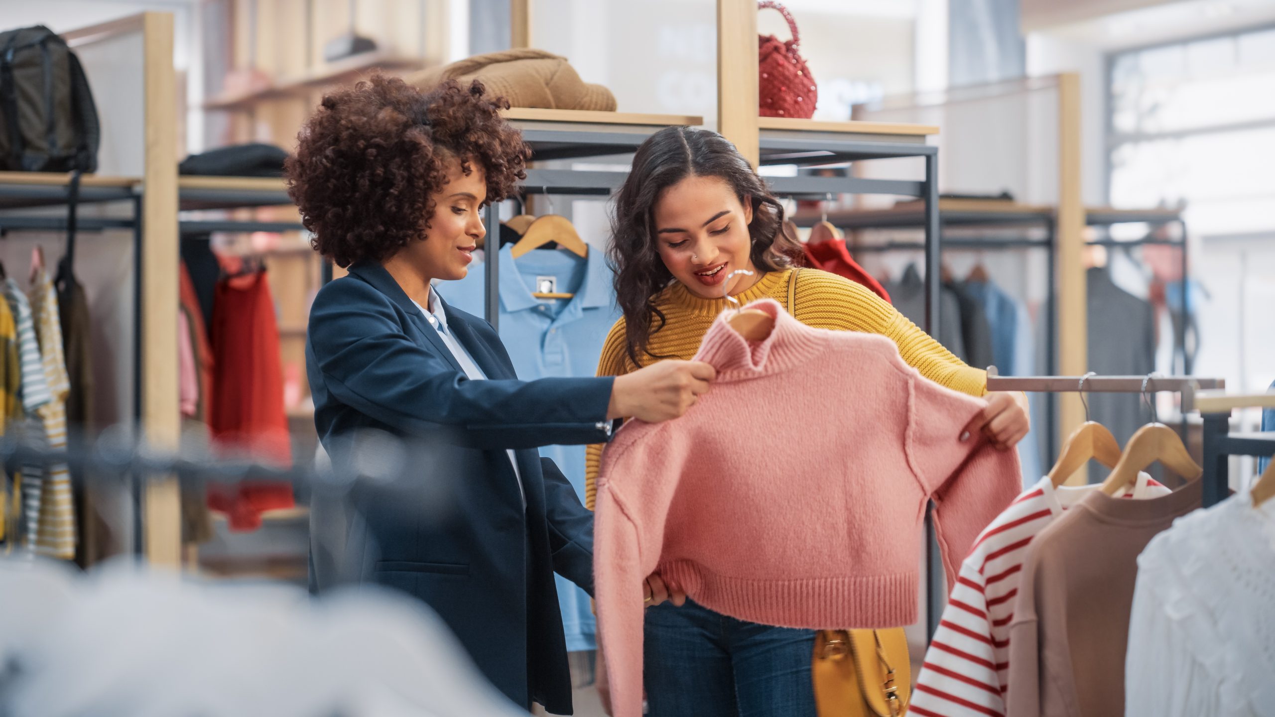cliente joven siendo atendida por asesora de moda en tienda de ropa scaled